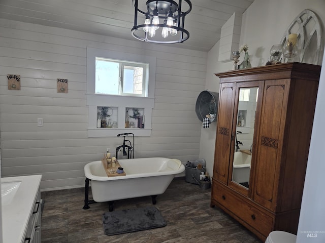 full bath featuring wood finished floors, vanity, a soaking tub, lofted ceiling, and a notable chandelier