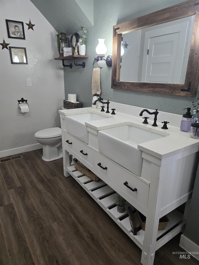 bathroom with wood finished floors, visible vents, toilet, vanity, and baseboards