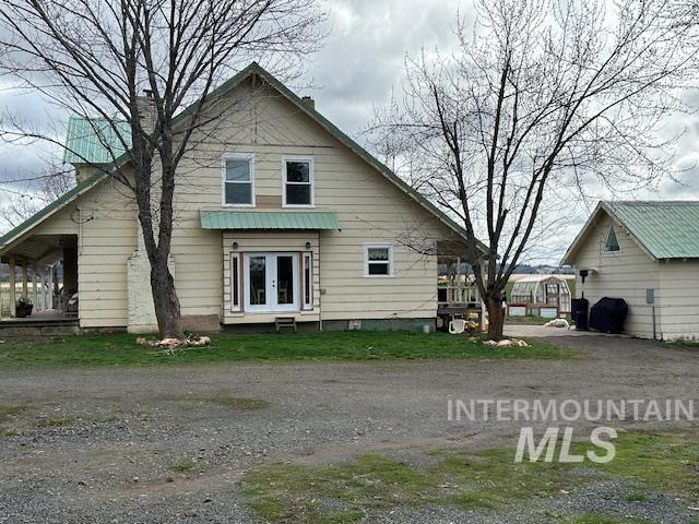 rear view of house featuring french doors, driveway, and a chimney