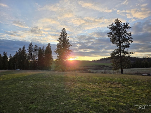 yard at dusk featuring a rural view