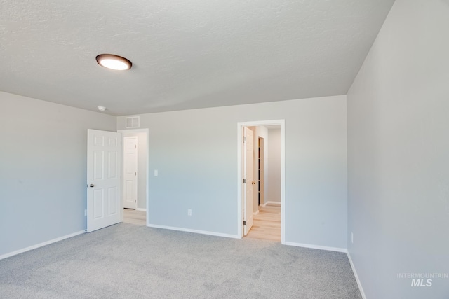 unfurnished room featuring light carpet and a textured ceiling