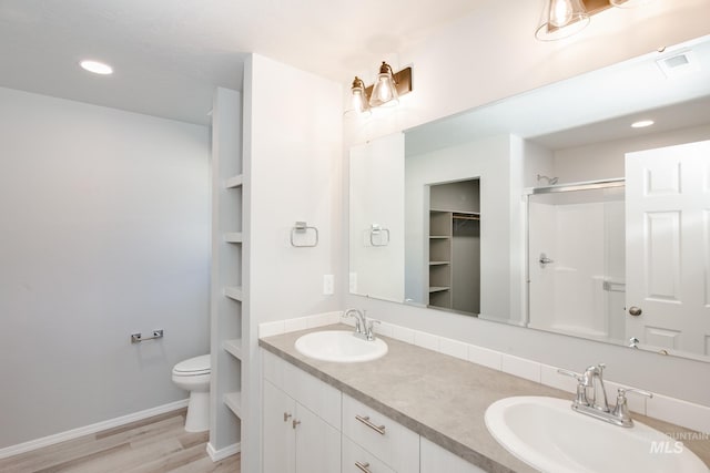 bathroom featuring built in features, oversized vanity, dual sinks, toilet, and wood-type flooring