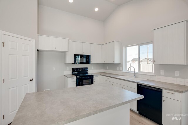 kitchen featuring white cabinetry, black appliances, sink, and light wood-type flooring