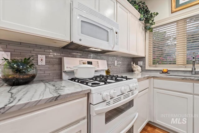 kitchen with white cabinetry, sink, light stone counters, white appliances, and decorative backsplash