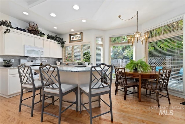 kitchen featuring white cabinets, decorative light fixtures, white appliances, and a notable chandelier