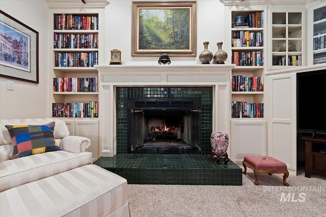 carpeted living room with a fireplace and built in shelves