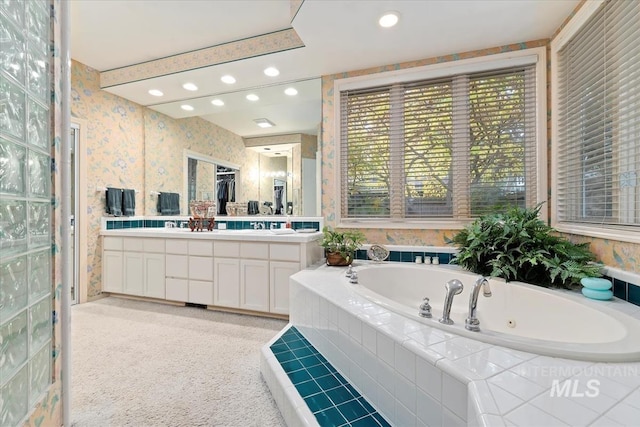 bathroom with tiled tub and vanity