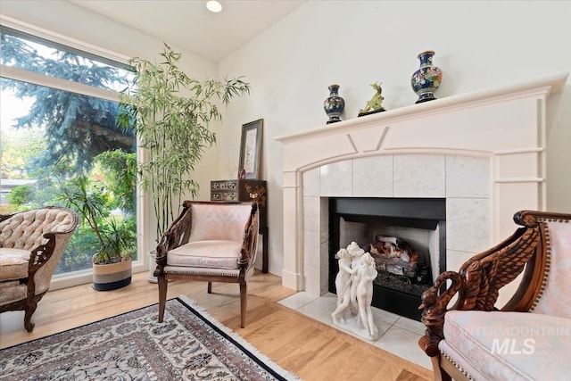 living area with a wealth of natural light, wood-type flooring, and a tile fireplace