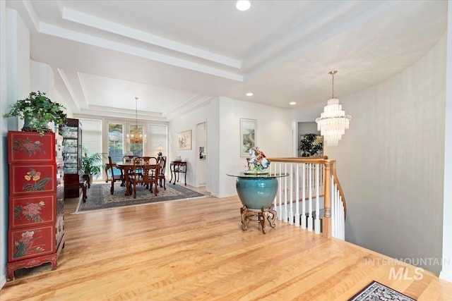 dining space with a raised ceiling, wood-type flooring, and a notable chandelier