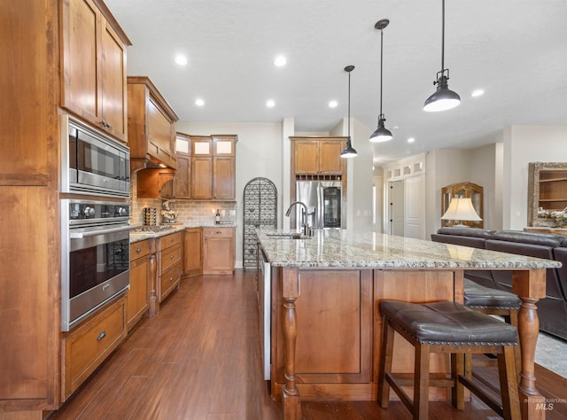 1573 E Commander St, Meridian, ID 83646 - kitchen featuring stainless steel appliances, a sink, dark wood-style flooring, tasteful backsplash, and brown cabinets
