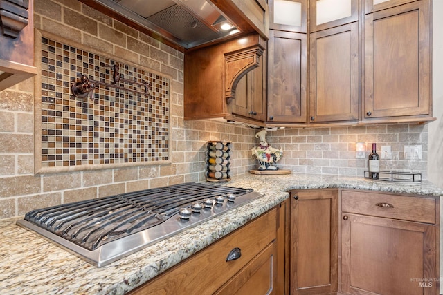 1573 E Commander St, Meridian, ID 83646 - kitchen with stainless steel gas stovetop, backsplash, glass insert cabinets, and light stone counters