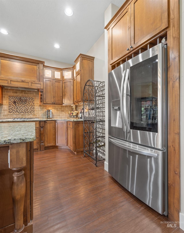 1573 E Commander St, Meridian, ID 83646 - kitchen with stainless steel refrigerator with ice dispenser, dark wood-type flooring, brown cabinetry, light stone counters, and backsplash