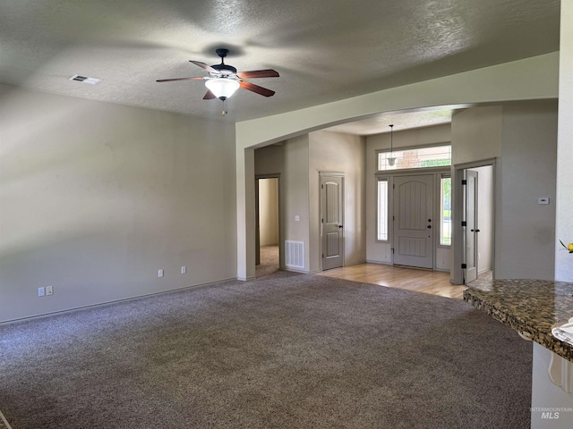 3669 N Dixon Ave, Meridian, ID 83646 - unfurnished living room with light colored carpet, ceiling fan, a textured ceiling, baseboards, and arched walkways