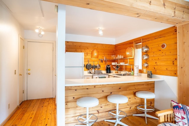 260 S 2nd Ave Unit 51, Ketchum, ID 83340 - kitchen featuring a sink, freestanding refrigerator, a kitchen breakfast bar, wooden walls, and light wood-style floors