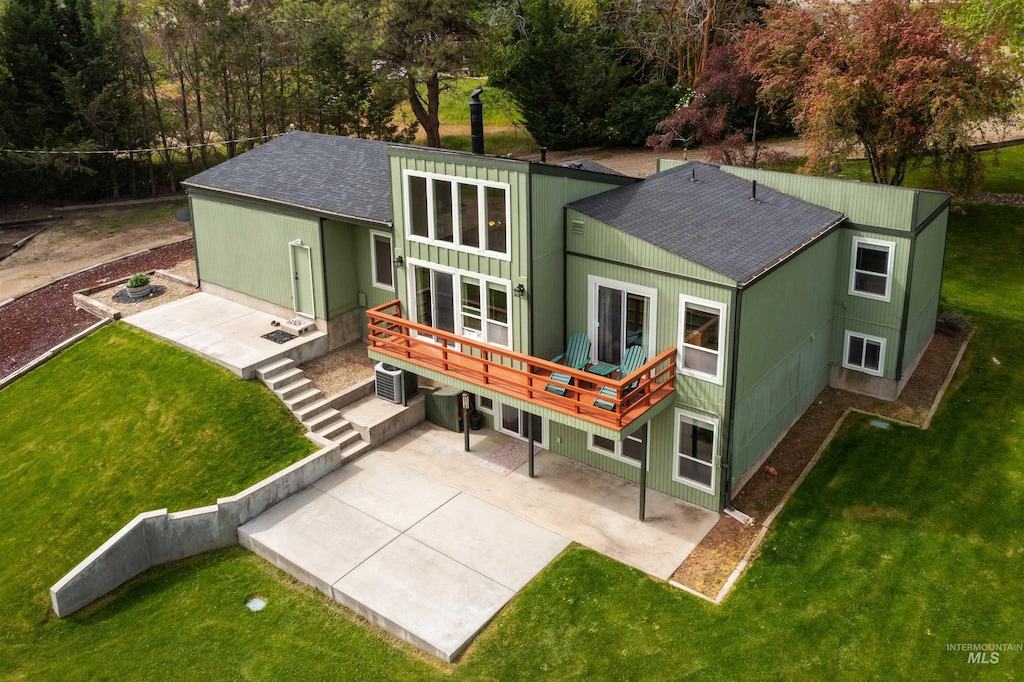 back of property featuring a shingled roof, a patio, and a yard