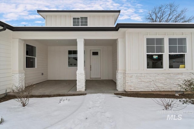 doorway to property featuring stone siding and board and batten siding