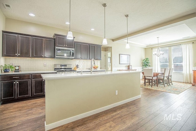 kitchen with appliances with stainless steel finishes, tasteful backsplash, and hardwood / wood-style flooring