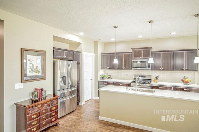 kitchen featuring decorative backsplash, appliances with stainless steel finishes, light countertops, dark brown cabinets, and a sink