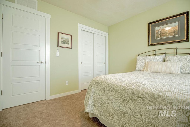 carpeted bedroom featuring baseboards, visible vents, and a closet