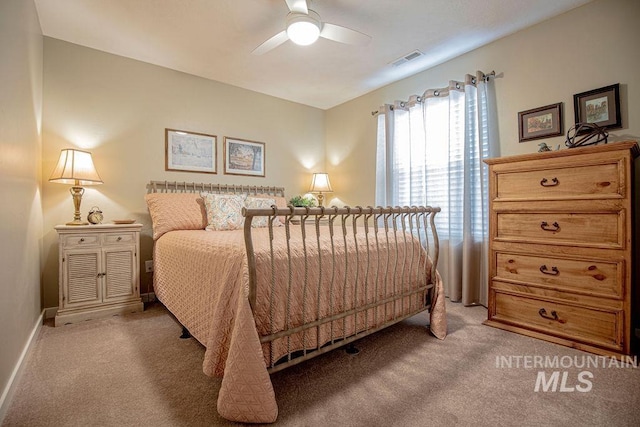 bedroom featuring light carpet, ceiling fan, visible vents, and baseboards