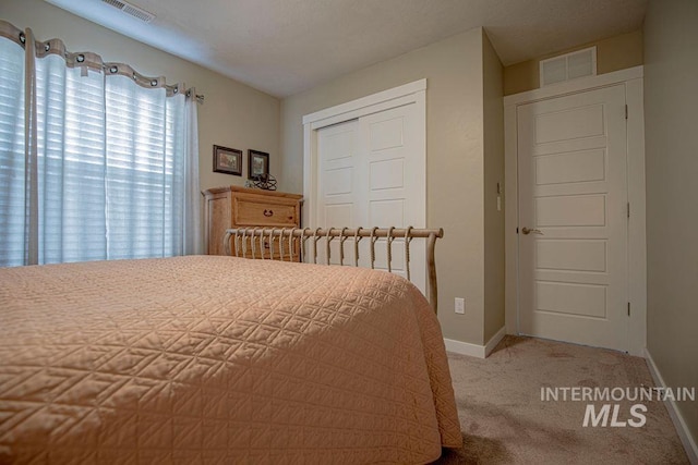 bedroom with baseboards, carpet, visible vents, and a closet