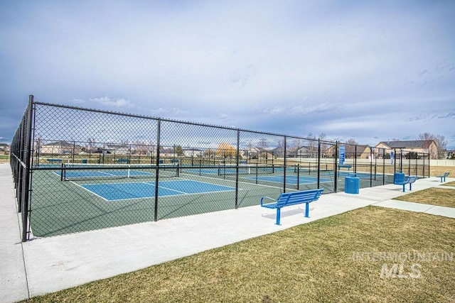 view of tennis court with a yard and fence