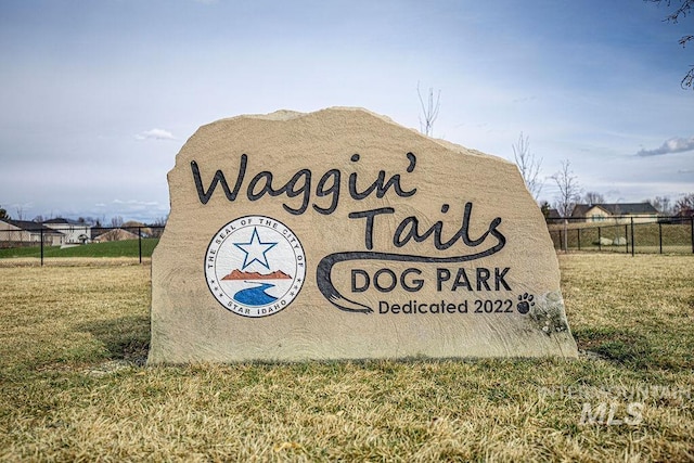 community sign featuring a lawn and fence