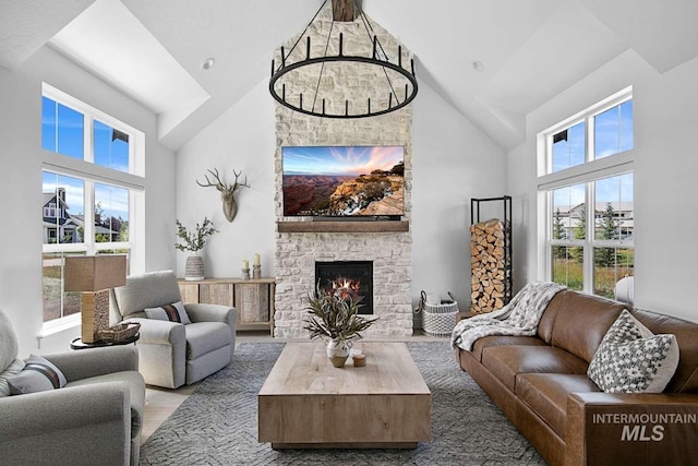 living room featuring hardwood / wood-style flooring, a stone fireplace, and high vaulted ceiling