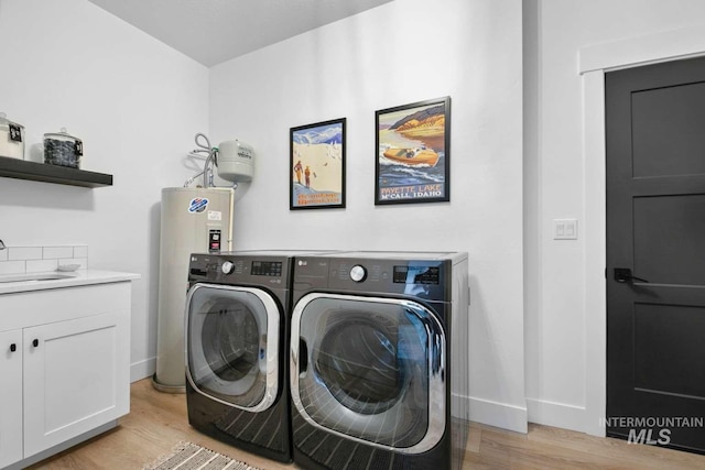 washroom with washing machine and clothes dryer, sink, cabinets, electric water heater, and light wood-type flooring