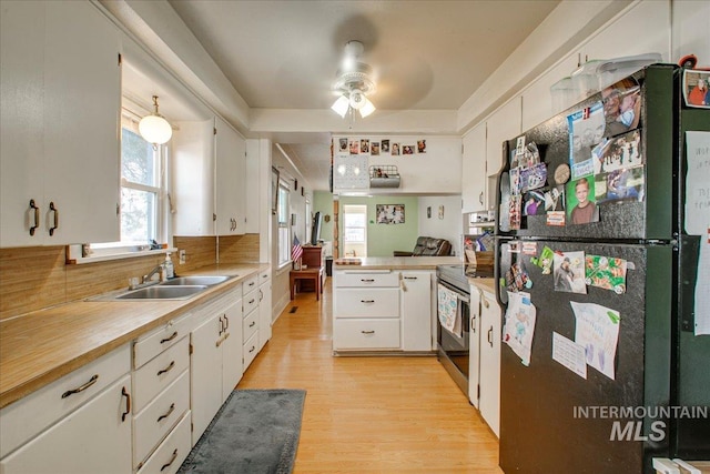 kitchen with ceiling fan, freestanding refrigerator, electric range, white cabinets, and a sink