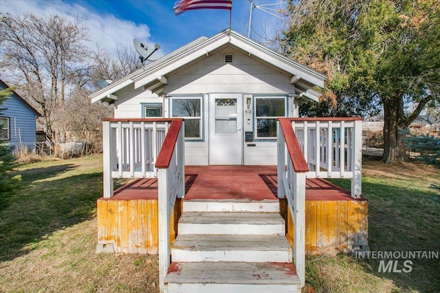 bungalow-style home with a wooden deck and a front yard