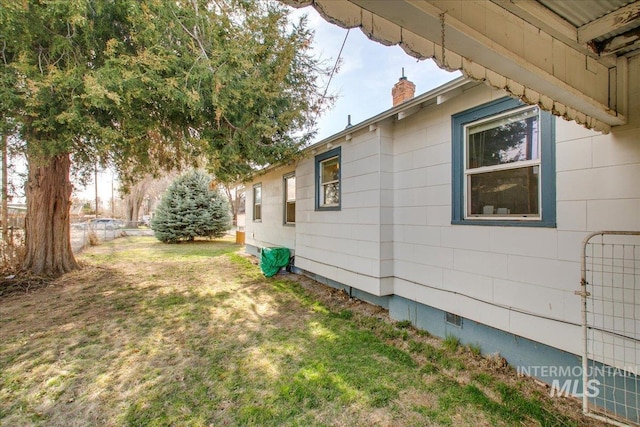 view of side of property featuring crawl space, a yard, and a chimney