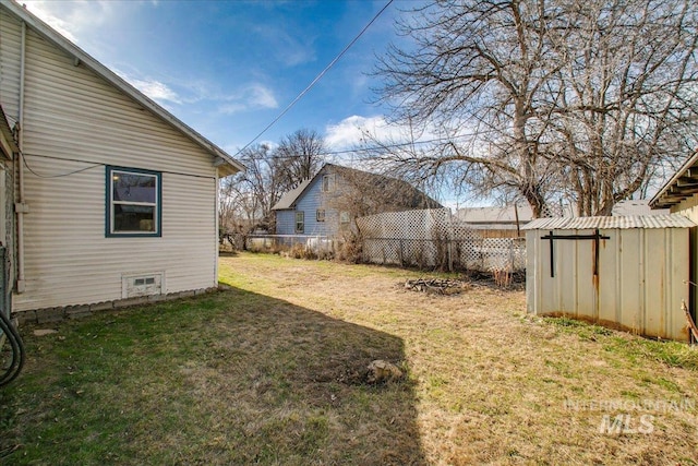 view of yard featuring a storage shed, an outdoor structure, and fence