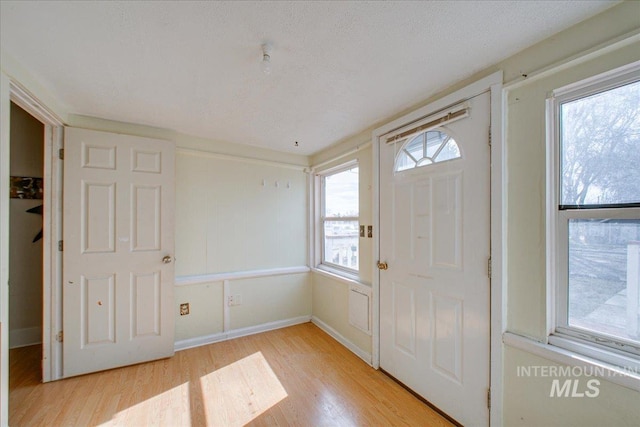 entrance foyer with light wood-type flooring, baseboards, and a textured ceiling