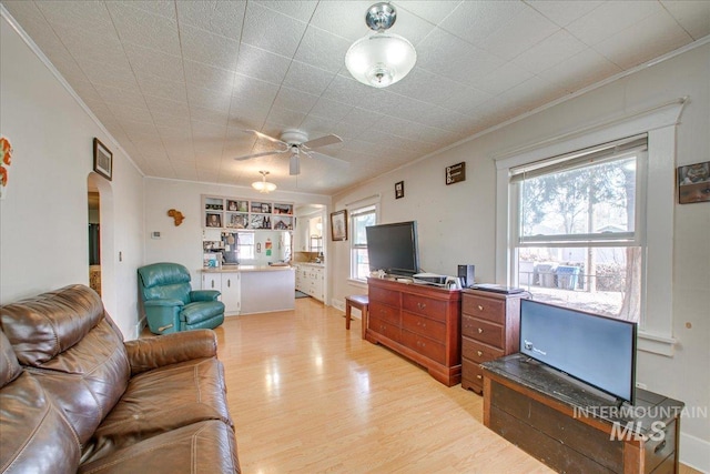 living area with crown molding, light wood-style flooring, and ceiling fan