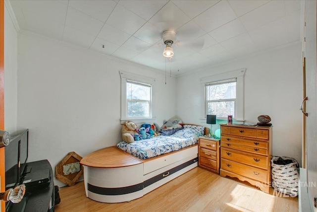 bedroom with light wood finished floors, crown molding, and a ceiling fan