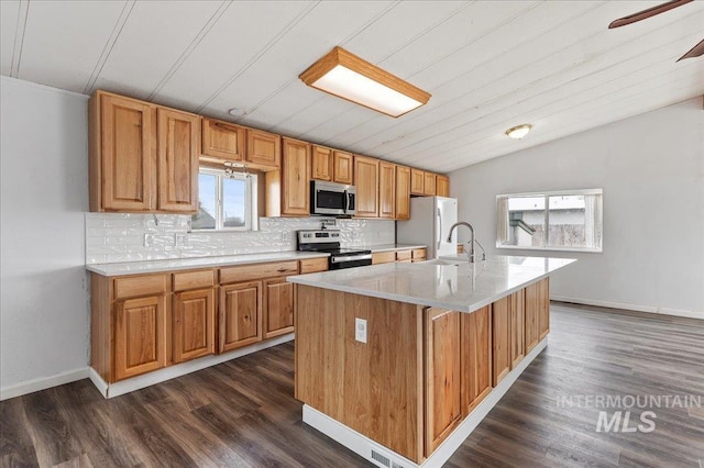 kitchen with light countertops, lofted ceiling, decorative backsplash, appliances with stainless steel finishes, and dark wood-style flooring