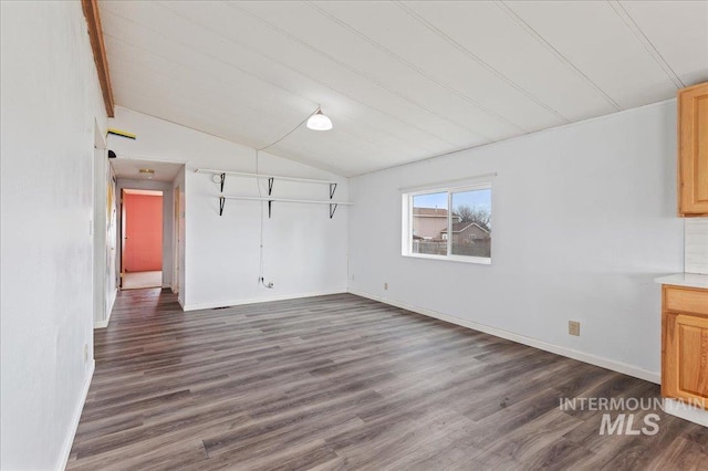 interior space featuring baseboards, lofted ceiling, and dark wood-type flooring