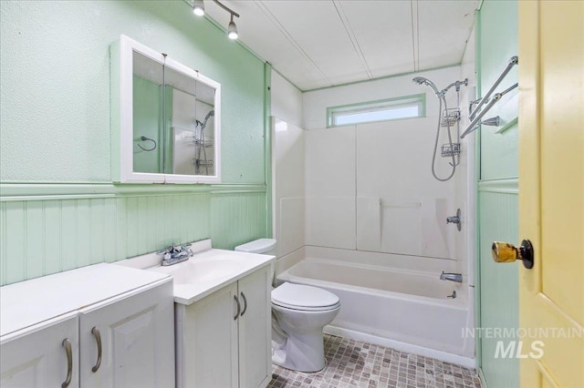 full bath featuring a wainscoted wall, toilet, vanity, tile patterned flooring, and shower / bathtub combination