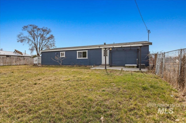 rear view of house with entry steps, a yard, and a fenced backyard