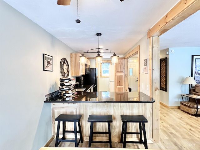 301 N Mission St Unit C3, Mccall, ID 83638 - kitchen featuring dark countertops, a peninsula, light wood-type flooring, black fridge, and a kitchen bar