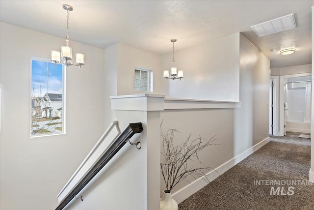 stairs with an inviting chandelier, carpet floors, and plenty of natural light