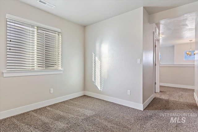 carpeted spare room featuring a chandelier