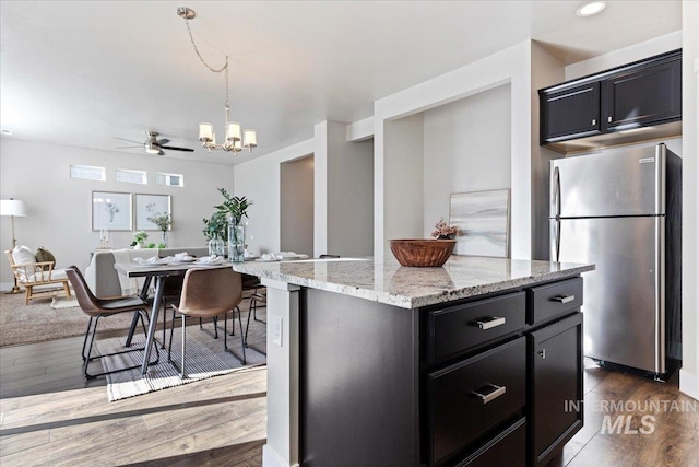 kitchen featuring a kitchen island, dark wood-type flooring, ceiling fan, and stainless steel fridge