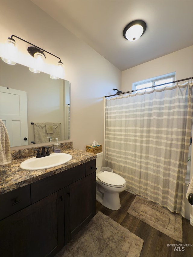 bathroom with hardwood / wood-style flooring, vanity, a shower with curtain, and toilet