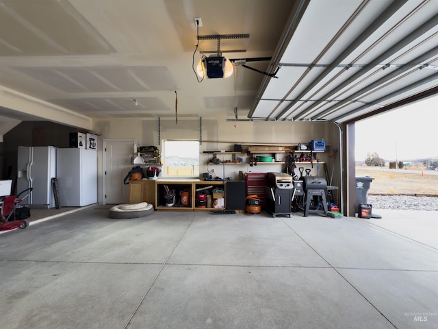 garage featuring a garage door opener, white fridge with ice dispenser, and a workshop area