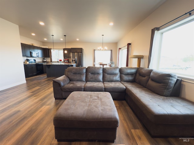living room with a chandelier, a wealth of natural light, and dark hardwood / wood-style flooring