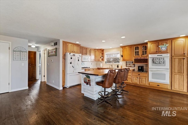 kitchen with wooden counters, white appliances, dark wood-type flooring, and a center island