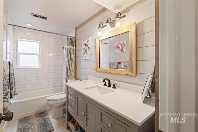 bathroom featuring toilet, wooden walls, vanity, visible vents, and shower / bath combo with shower curtain