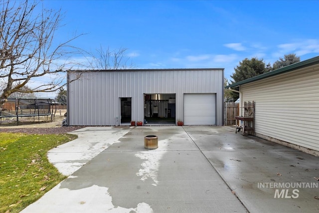 detached garage featuring a trampoline and fence